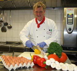 Küchenpersonal mit frischem Gemüse im Vordergrund